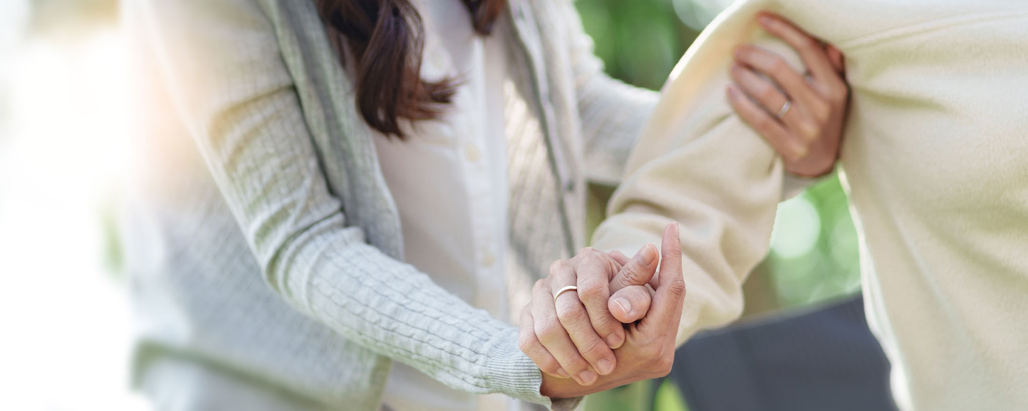 Eine weibliche Pflegekraft stÃ¼tz eine Ã¤ltere Frau und hÃ¤lt ihr zur UnterstÃ¼tzung die Hand